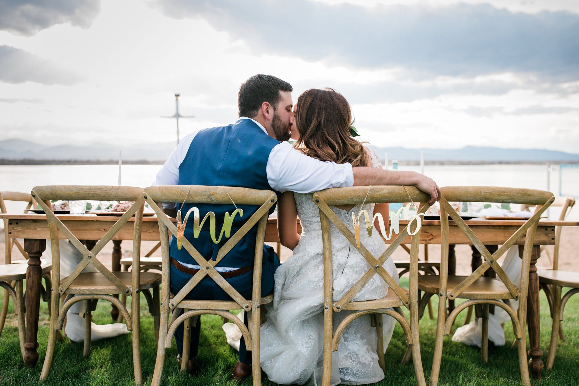 colorado bride and groom lakeside at reception table kissing