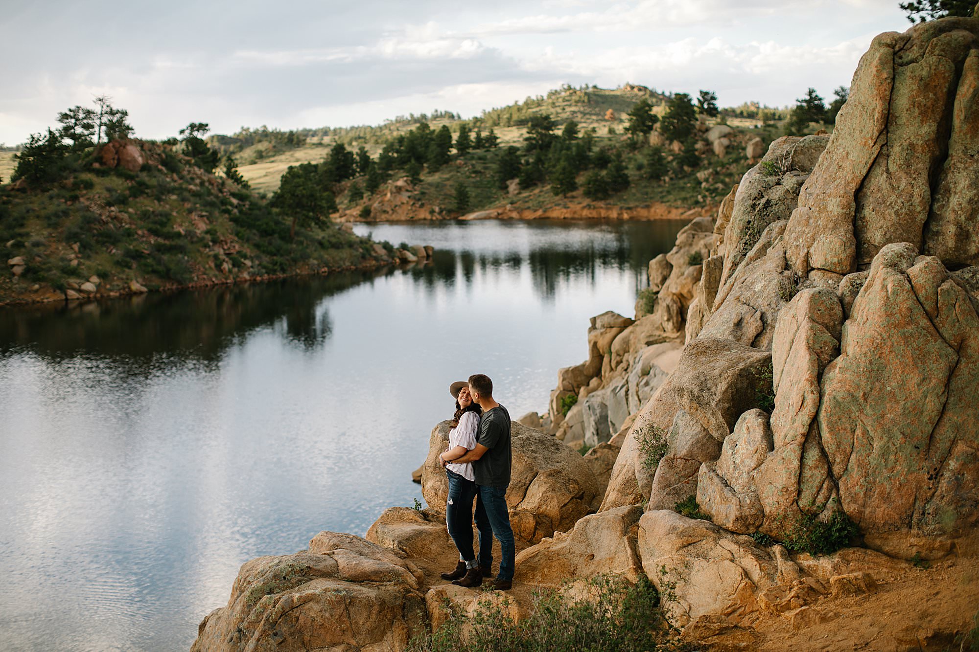 couple in mountains by water and cliffs for engagement