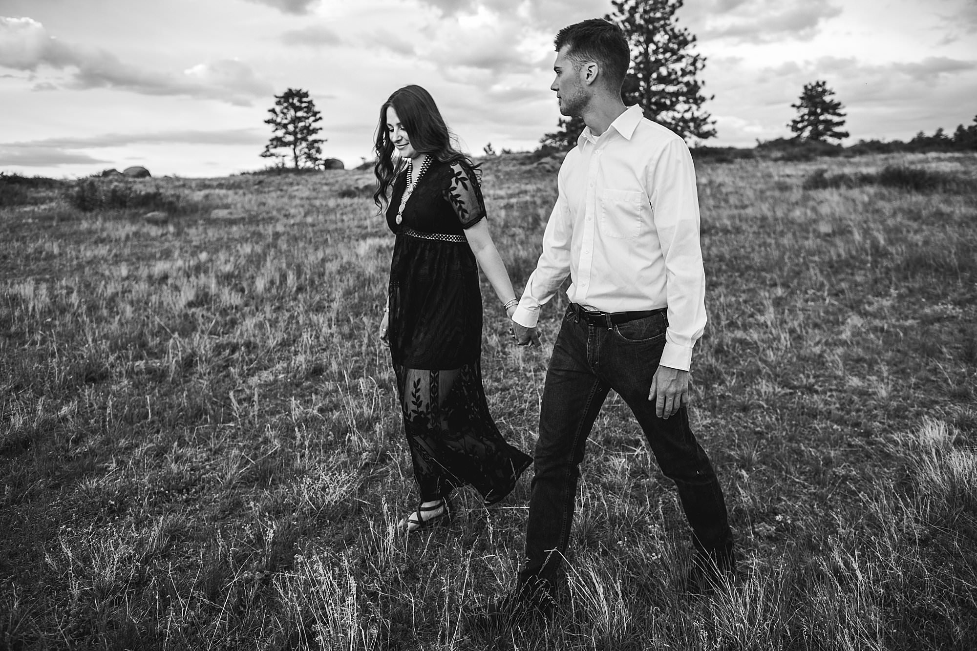 black and white photo of couple walking through grass