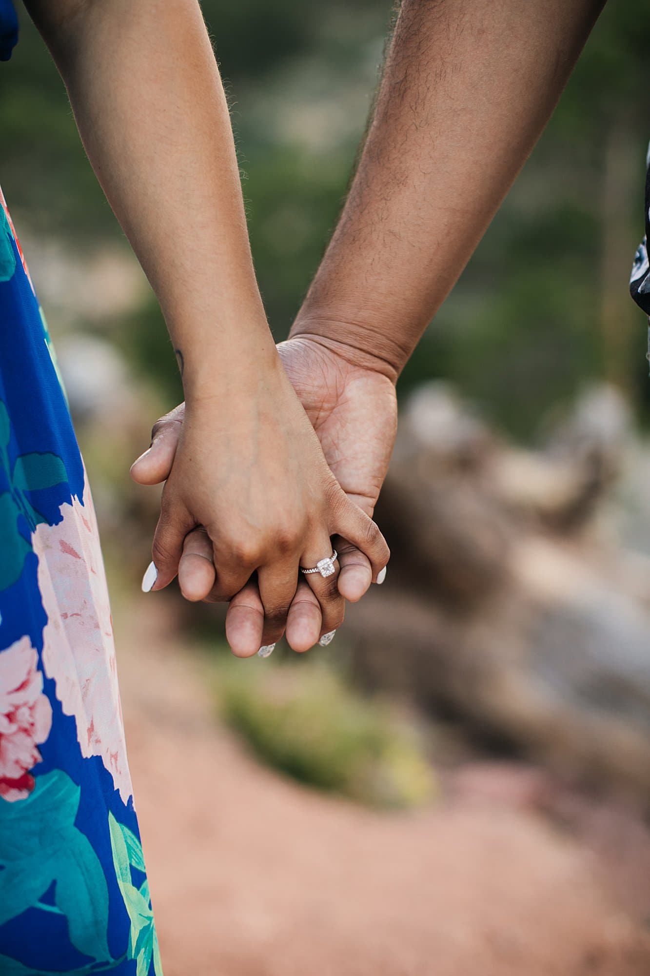 hands with engagement ring on red trail